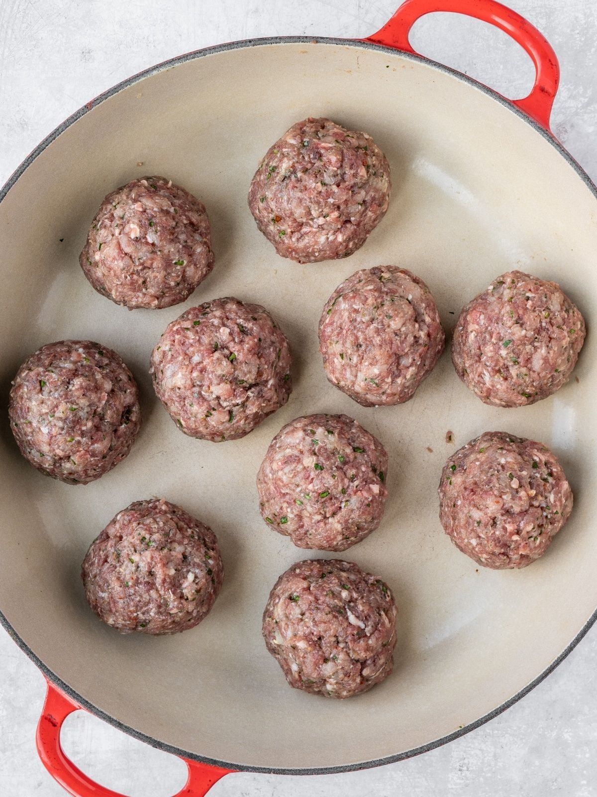 Raw meatballs in a shallow pan.
