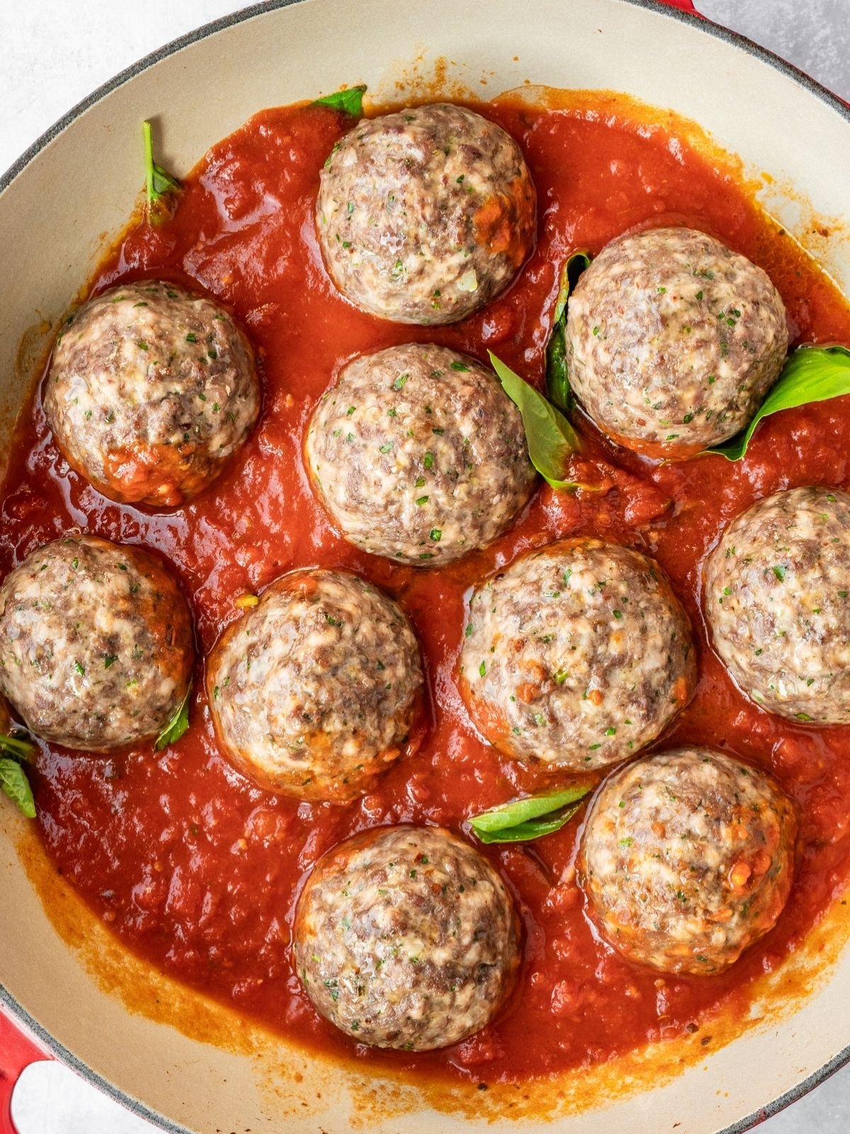 Adding the marinara sauce to the pan along with fresh basil.