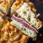 Cross-section of a muffuletta slice showing the deli meat and cheese.