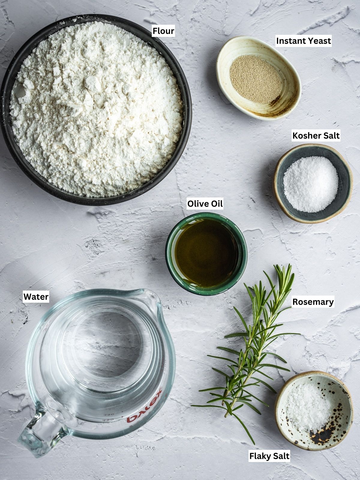 Muffuletta sandwich bread ingredients on a board with individual labels.
