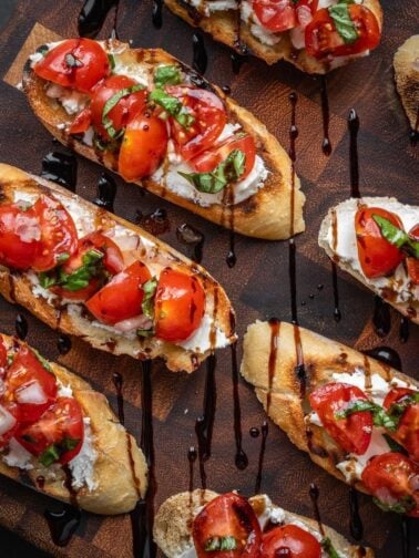 Cherry tomato and goat cheese bruschetta on a wooden board.