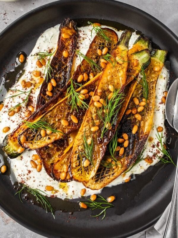 Charred zucchini over garlic yogurt garnished with pine nuts and dill.