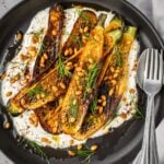 Charred zucchini over garlic yogurt garnished with pine nuts and dill.