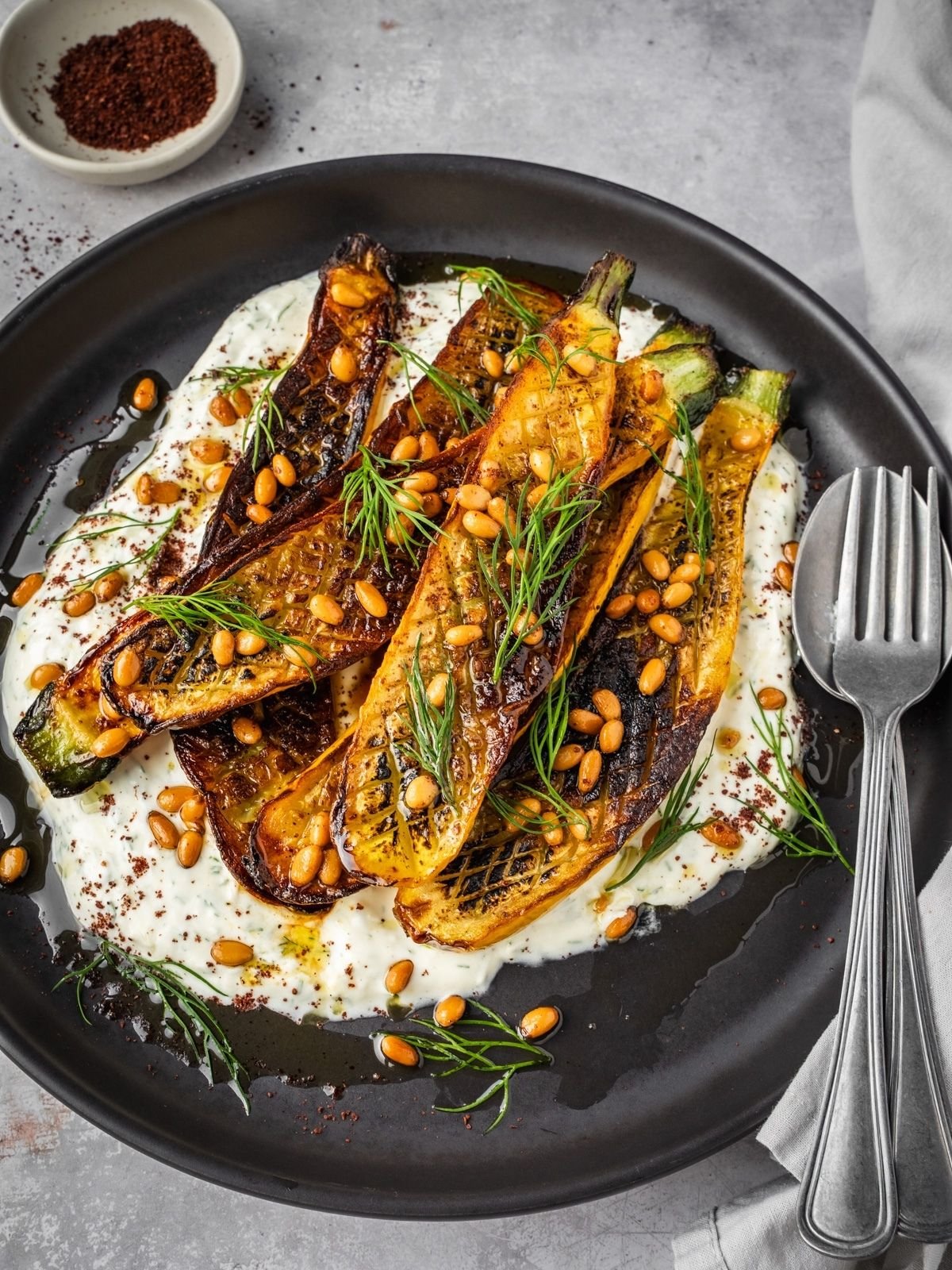 Charred zucchini over garlic yogurt garnished with pine nuts and dill.