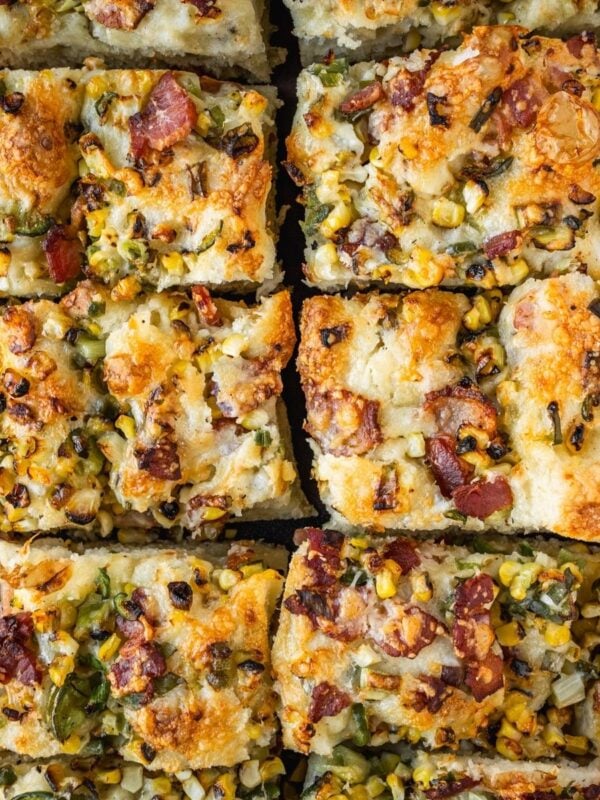 Corn jalapeno bacon focaccia slices on a wooden board.