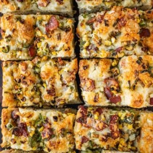 Corn jalapeno bacon focaccia slices on a wooden board.