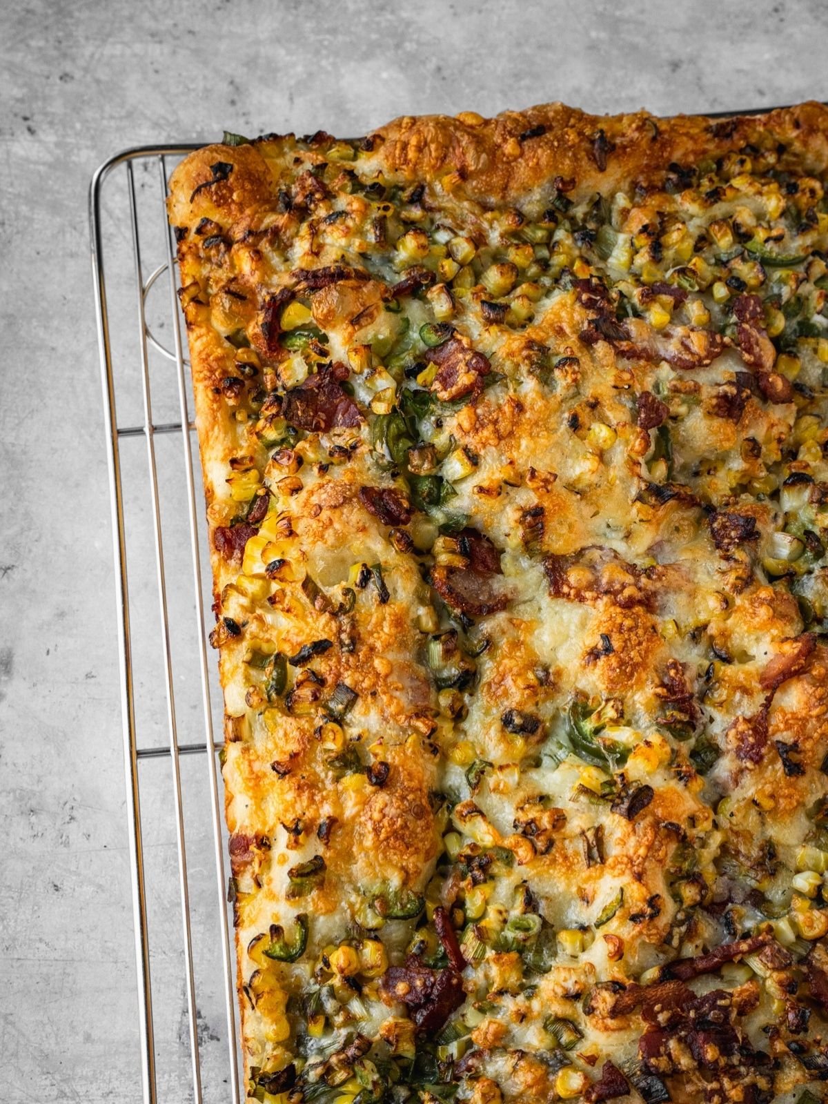 Corn jalapeno bacon focaccia cooling on a rack.
