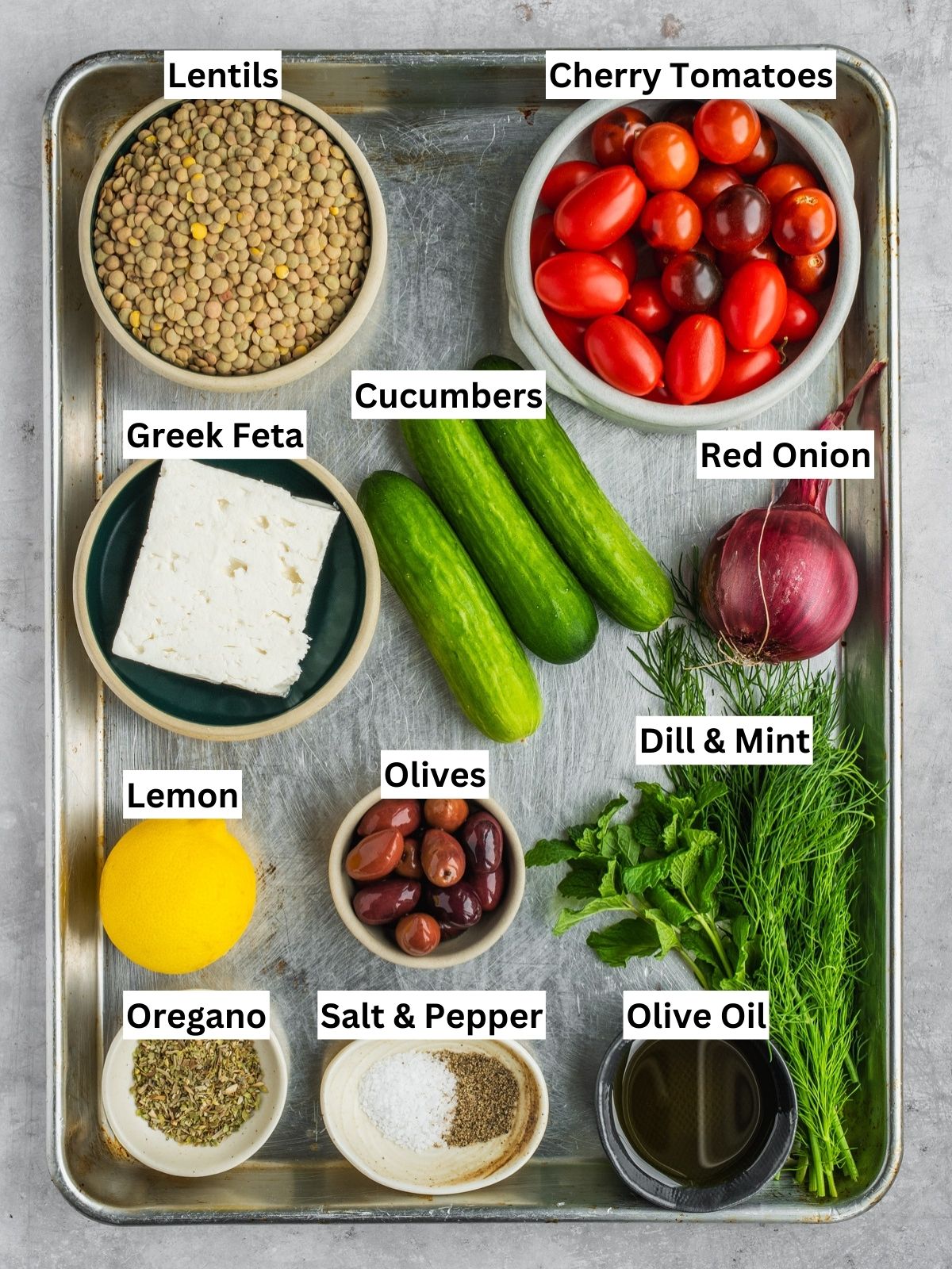 Greek-inspired lentil salad recipe ingredients with individual labels on a metal tray.