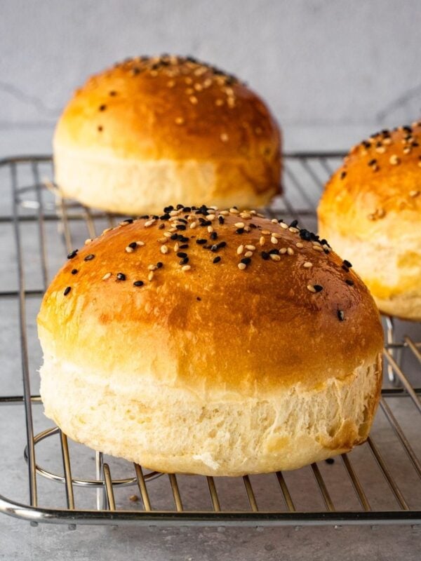 Homemade hamburger buns resting on a cooling rack.