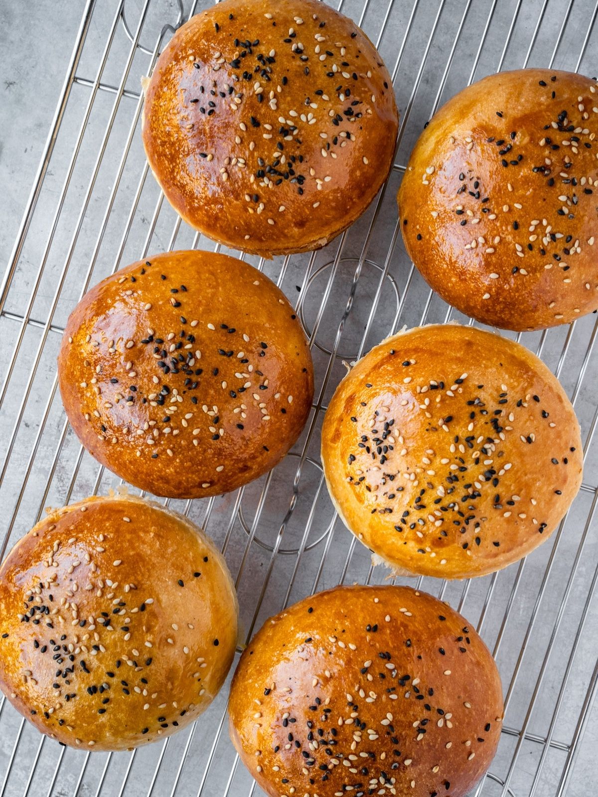 Homemade hamburger buns resting on a cooling rack.