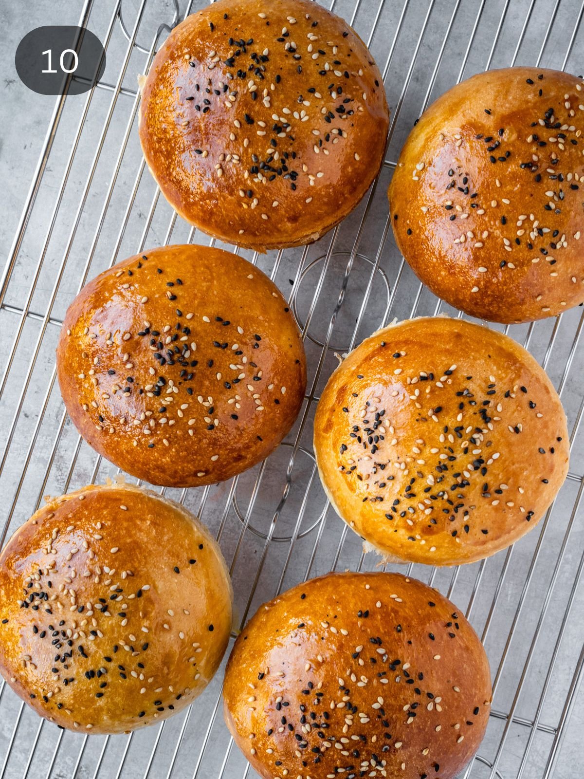 Homemade hamburger buns resting on a cooling rack.