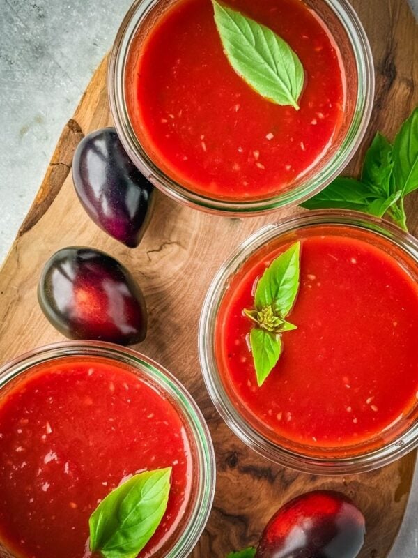 Mason jars with midnight Roma tomato sauce on a wooden board.