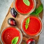 Mason jars with midnight Roma tomato sauce on a wooden board.