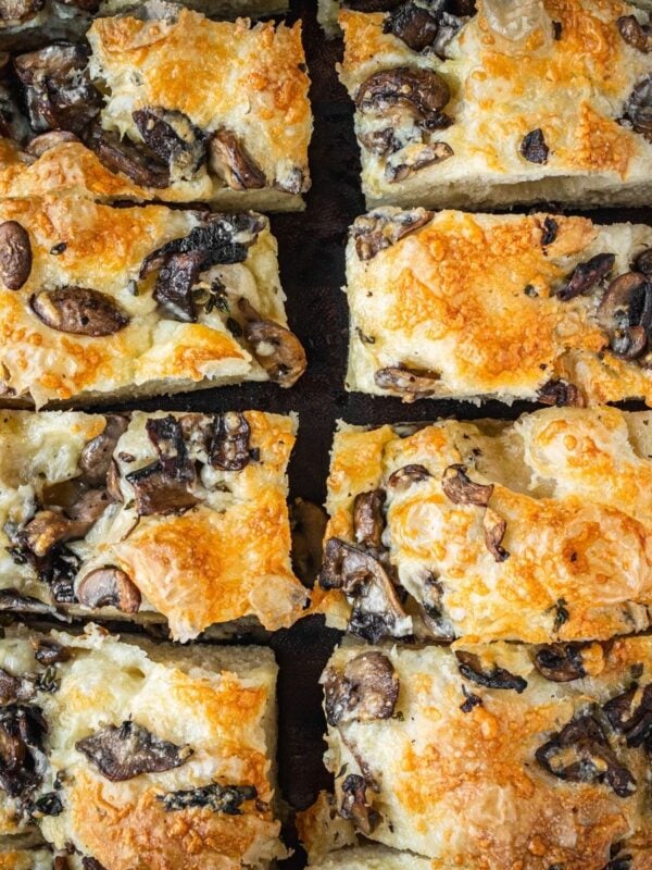 Slices of mushroom cheddar focaccia on a wooden board.