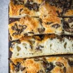 Slices of mushroom cheddar focaccia on a wooden board.