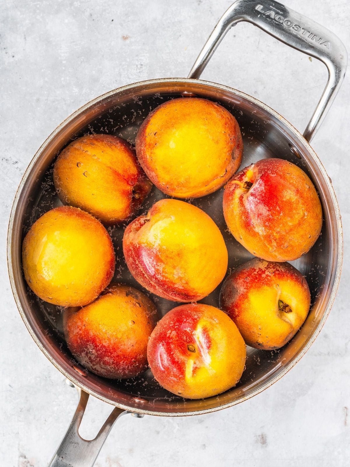 Peaches simmering in a pot with boiling water.