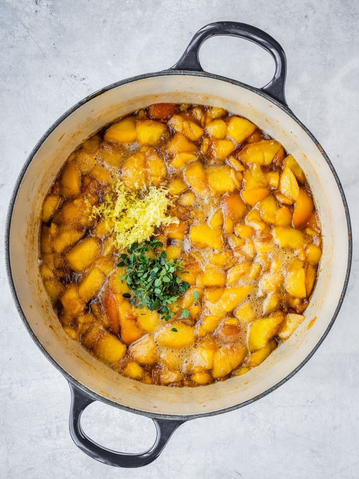 Recipe step showing the addition of flavoring, in this case lemon zest and thyme, to the half-way cooked jam.