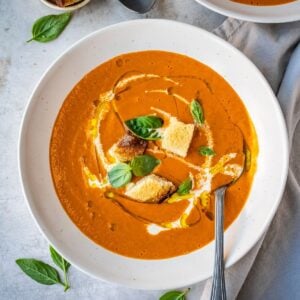 Bowl of tomato soup with croutons and basil.