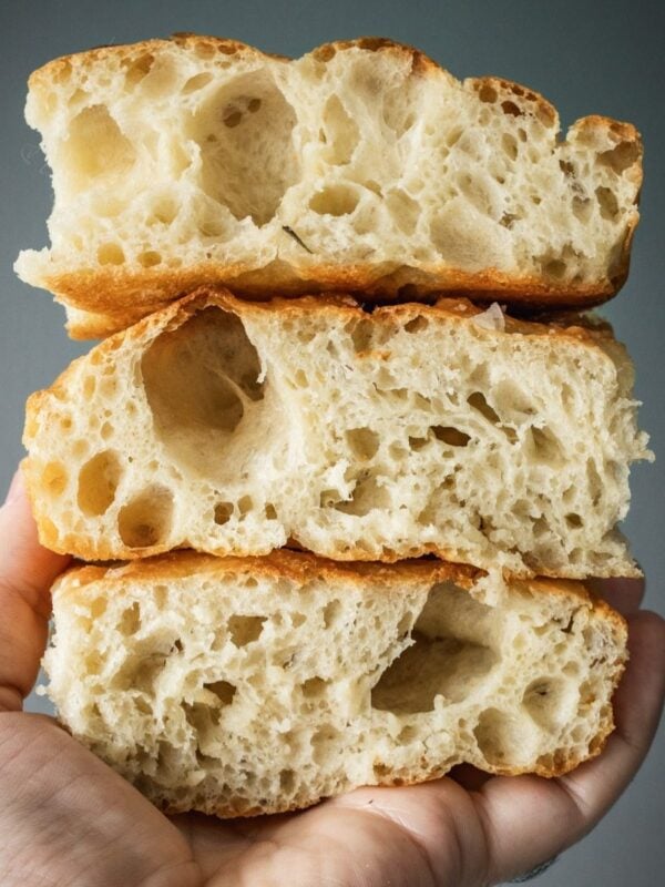 A hand holding 3 fluffy focaccia slices.