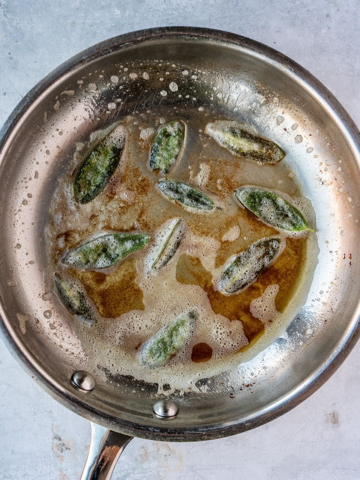 Frying pan with butter and sage leaves.
