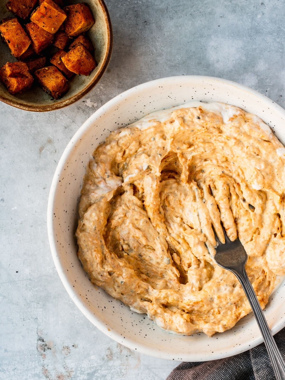 Bowl showing the mafghoussa being prepared by mashing the roasted squash with the labneh base.