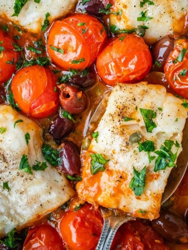 Baked cod in a puttanesca sauce with cherry tomatoes, olives, capers and garnished with parsley.