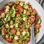 Mediterranean Lentil Salad with cooked green lentils, cherry tomatoes, cucumbers, mozzarella balls and fresh basil in a large serving bowl.