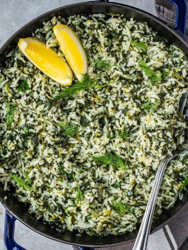Spanakorizo Greek Rice with spinach in a large pot, garnished with lemon wedges and extra fresh dill.