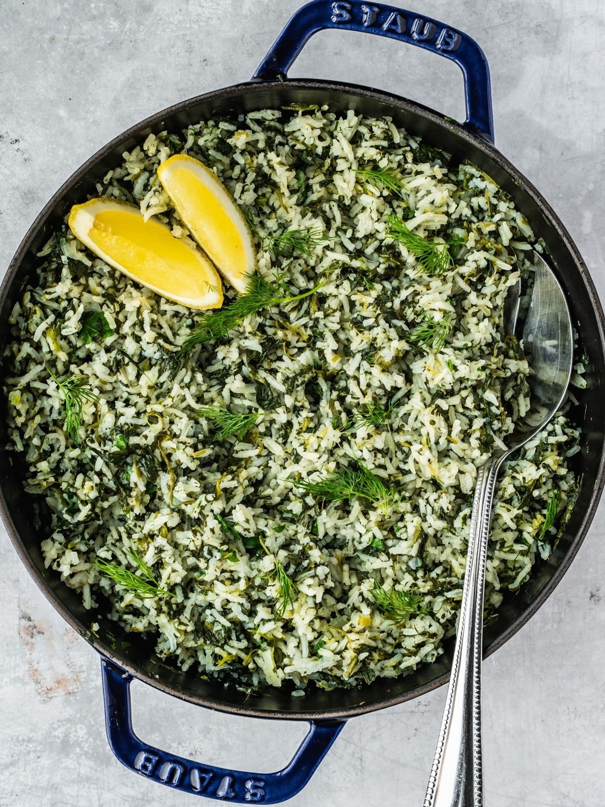 Spanakorizo Greek Rice with spinach in a large pot, garnished with lemon wedges and extra fresh dill.