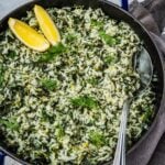 Spanakorizo Greek Rice with spinach in a large pot, garnished with lemon wedges and extra fresh dill.