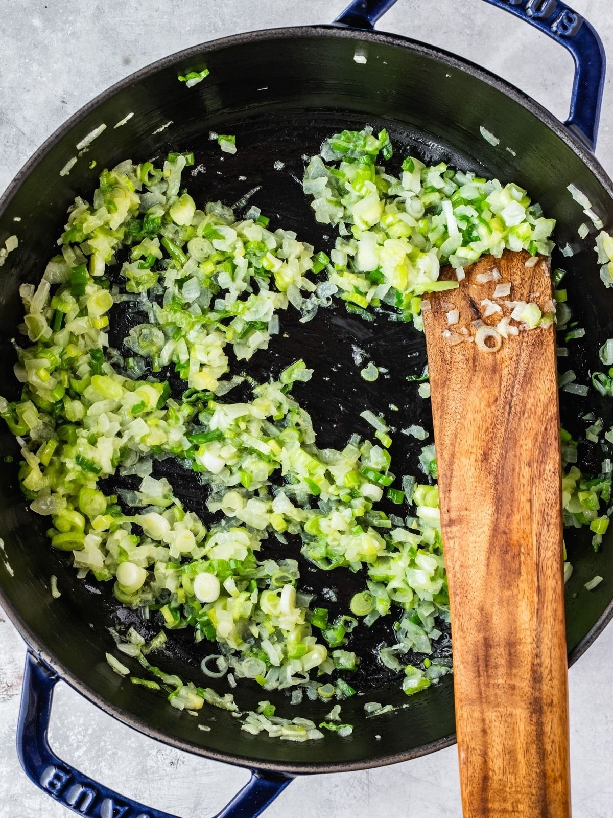 Diced onion and green onion frying in a pot.
