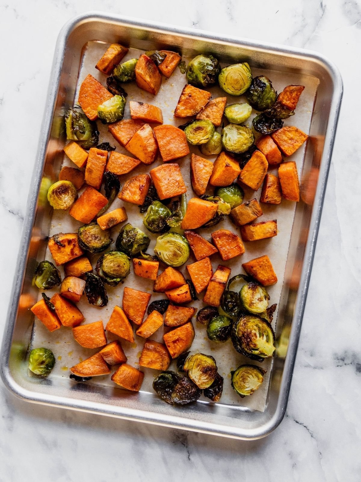 Baking tray with roasted sweet potatoes and Brussels sprouts.