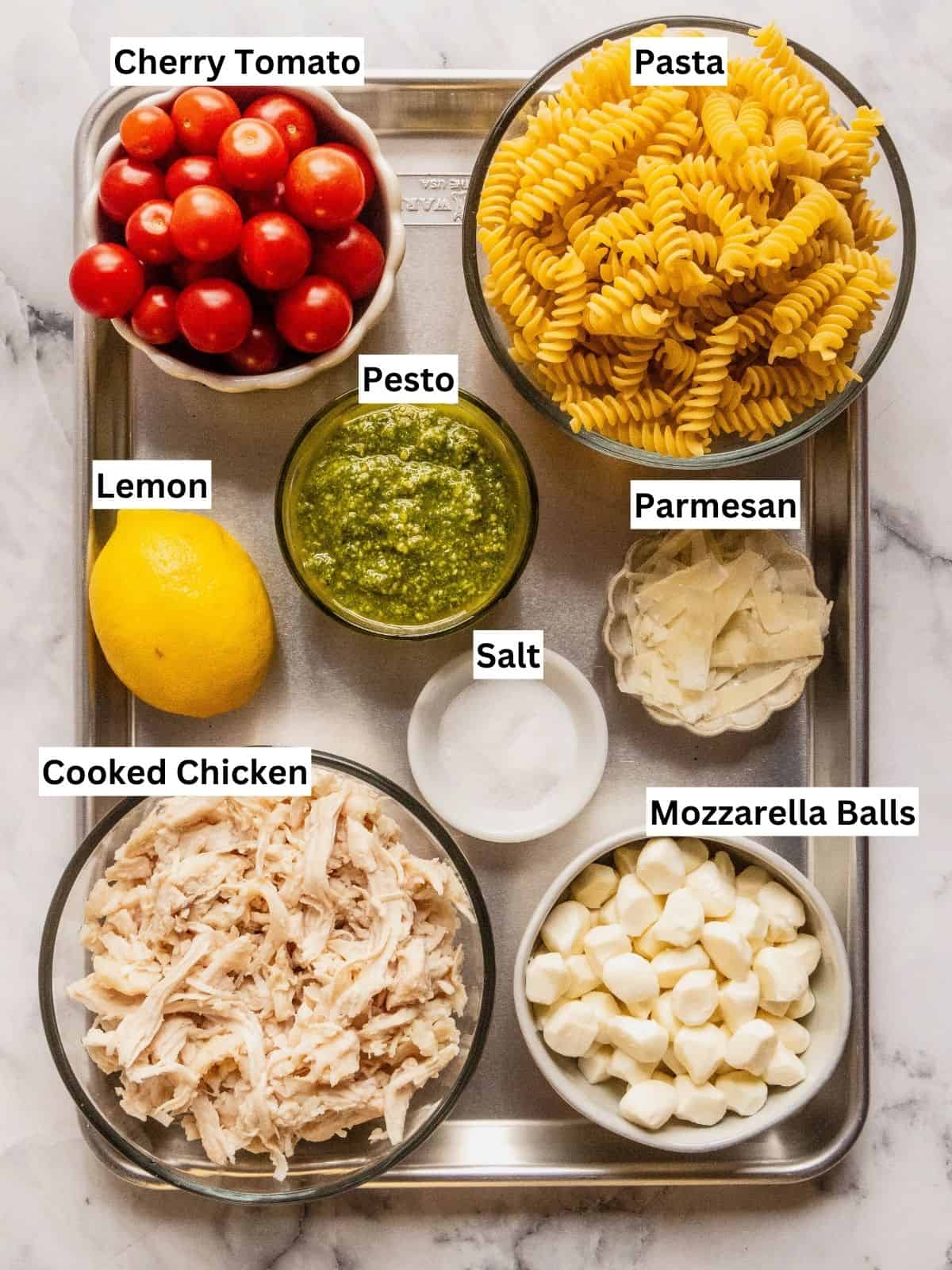Chicken and pesto pasta salad recipe ingredients with individual labels on a metal tray.