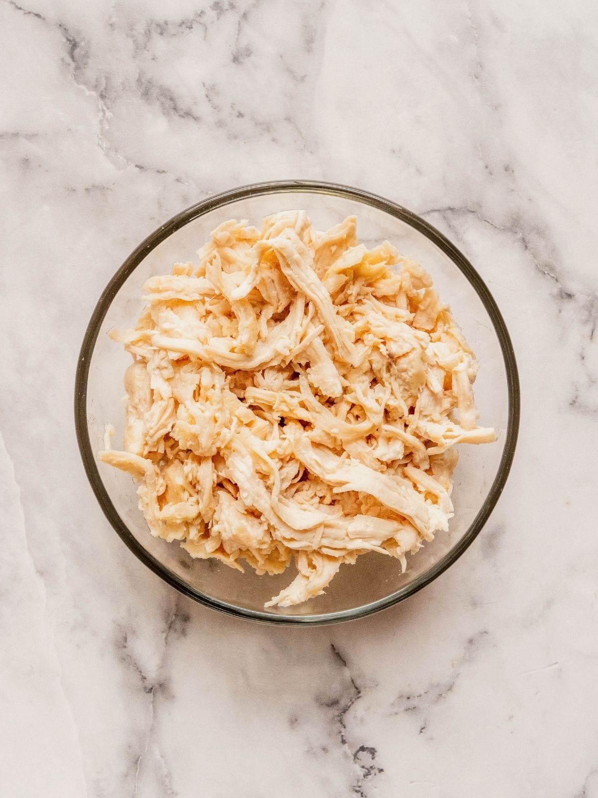 Glass bowl with shredded chicken.