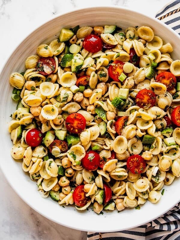 Mediterranean Chickpea Pasta Salad with cherry tomatoes and chopped cucumber in a large serving bowl.