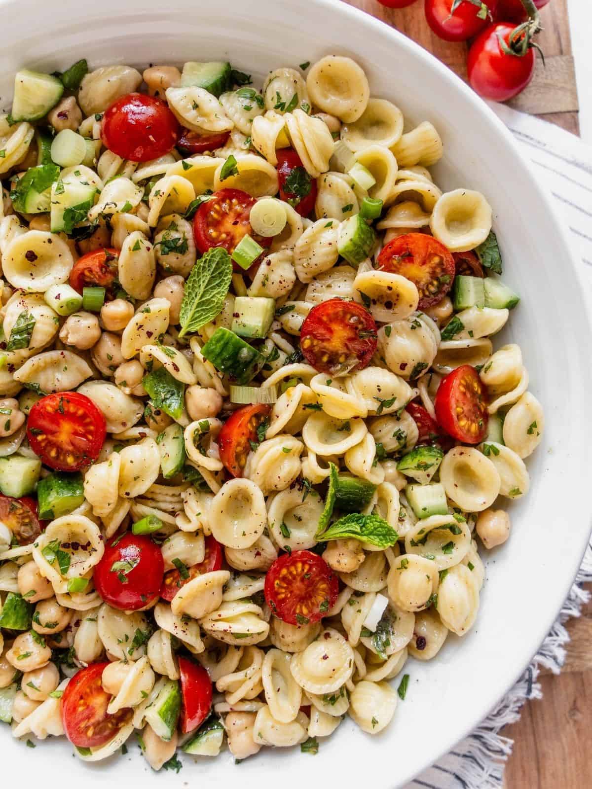 Mediterranean Chickpea Pasta Salad with cherry tomatoes and chopped cucumber in a large serving bowl.