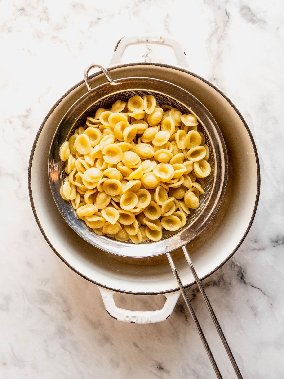 Orecchiette pasta draining in a sieve.