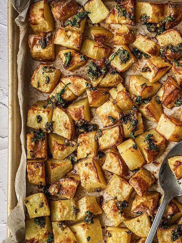 Finished batata harra tray showing the baked potato cubes drizzled with the dressing.