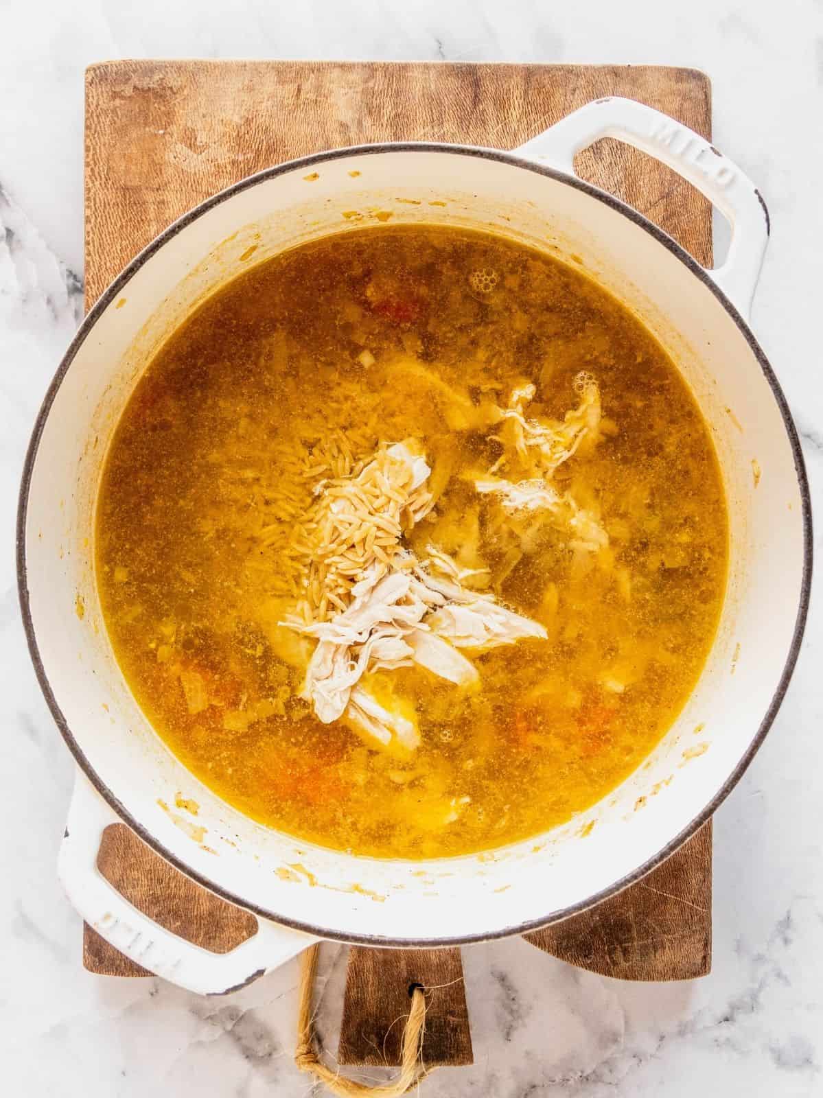 Recipe step showing the addition of the dry orzo to the soup base.