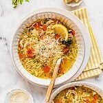Lemon chicken orzo soup garnished with herbs and parmesan cheese in a bowl.