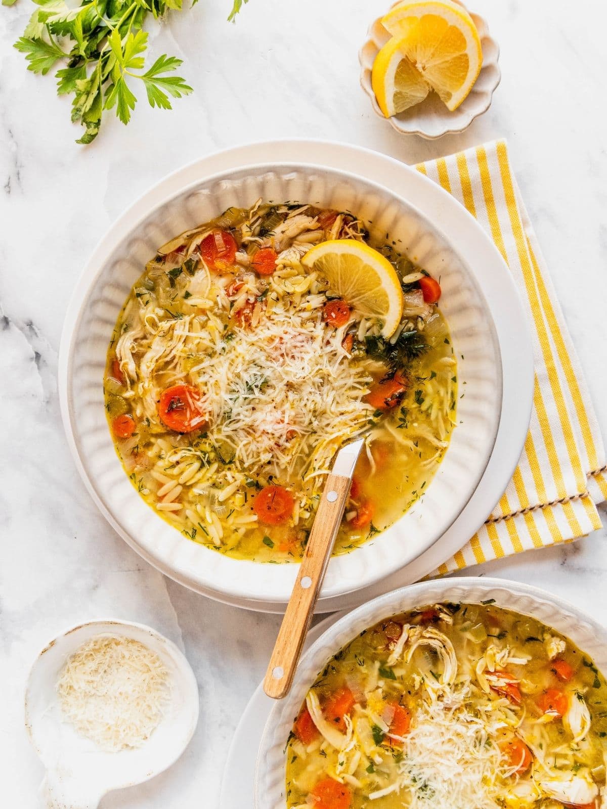 Lemon chicken orzo soup garnished with herbs and parmesan cheese in a bowl.
