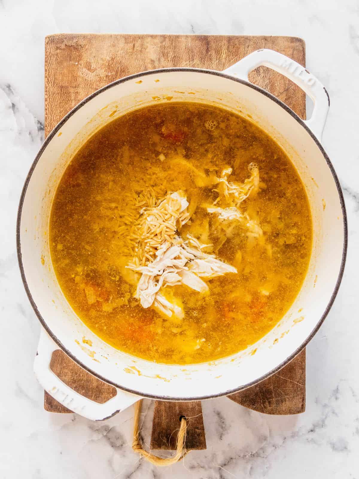 Recipe step showing the addition of the dry orzo to the soup base.