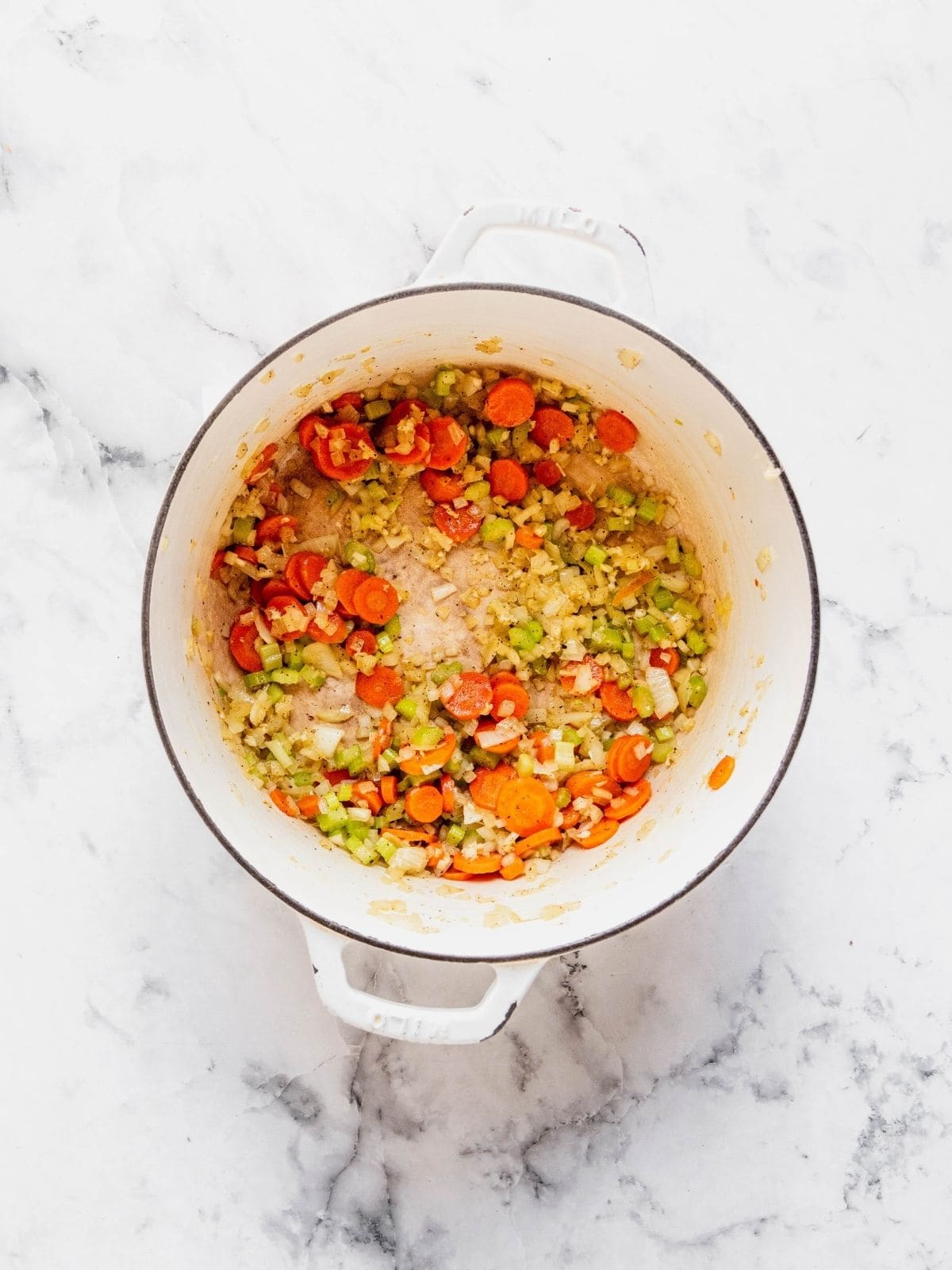 Recipe step showing the sautéing of the celery, carrots, onion and garlic in a soup pot.