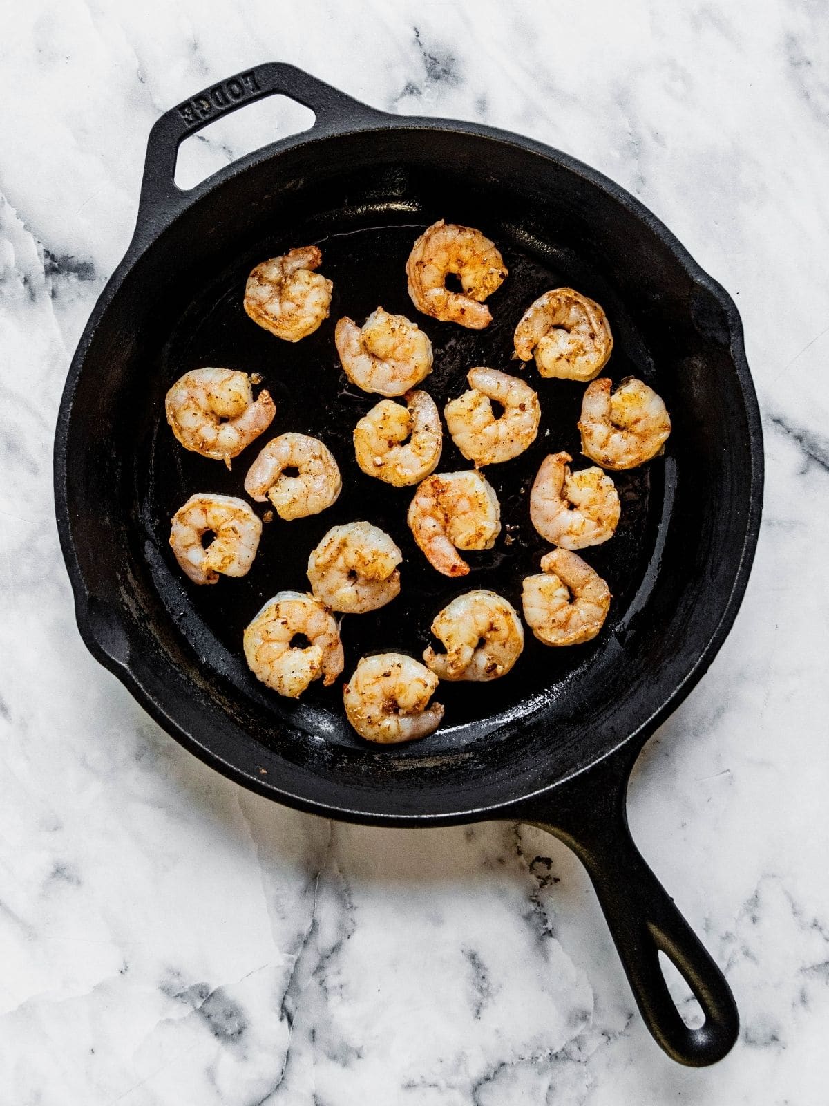 Seasoned shrimp cooking in a cast iron pan.