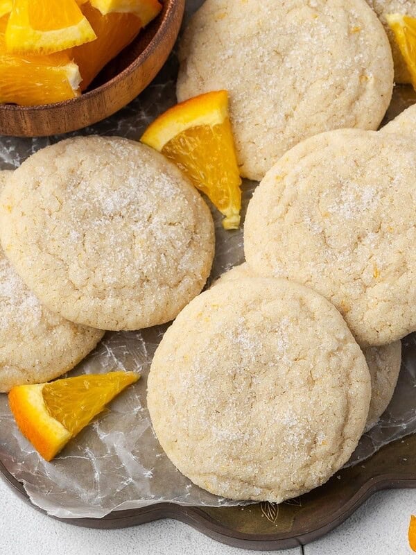 Orange sugar cookies on a parchment paper-lined tray.