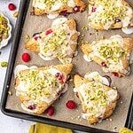 Pistachio and Cranberry Scones garnished with icing and crushed pistachios on a baking tray.