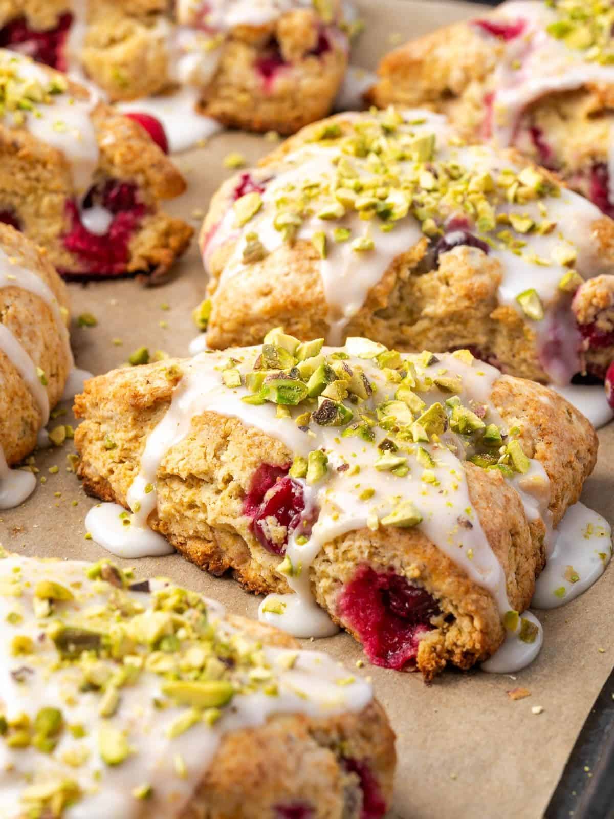 Pistachio and Cranberry Scones garnished with icing and crushed pistachios on a baking tray.