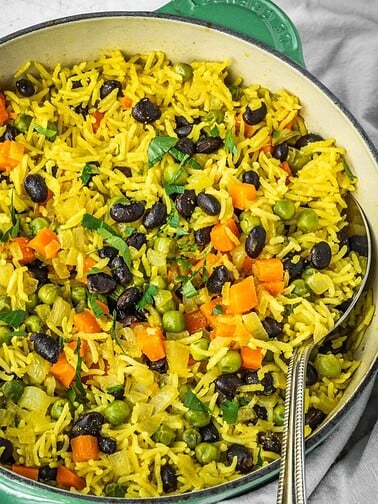 Pot of yellow rice studded with vegetables and black beans.