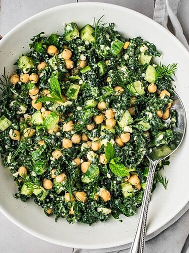 Bowl of kale and chickpea salad with feta and herbs.