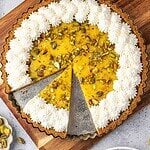Lemon curd tart with pistachios, decorated with piped whipped cream.